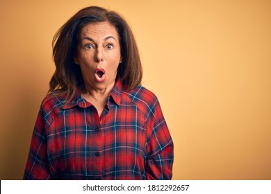 Middle Age Beautiful Woman Wearing Casual Shirt Standing Over Isolated Yellow Background Afraid And Shocked With Surprise And Amazed Expression, Fear And Excited Face.