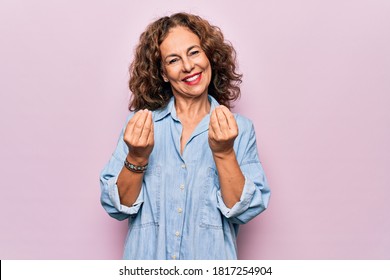 Middle Age Beautiful Woman Wearing Casual Denim Shirt Standing Over Pink Background Doing Money Gesture With Hands, Asking For Salary Payment, Millionaire Business