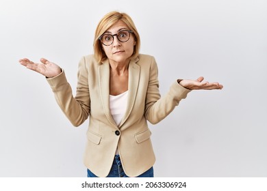 Middle age blonde business woman standing over isolated background clueless and confused expression with arms and hands raised. doubt concept.  - Powered by Shutterstock