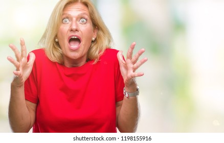 Middle age blonde woman over isolated background crazy and mad shouting and yelling with aggressive expression and arms raised. Frustration concept.