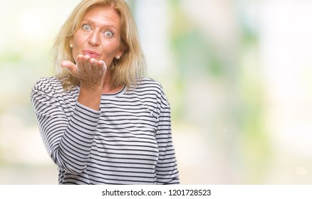 Middle age blonde woman over isolated background looking at the camera blowing a kiss with hand on air being lovely and sexy. Love expression.