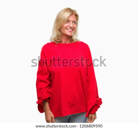Middle age blonde woman over isolated background looking away to side with smile on face, natural expression. Laughing confident.