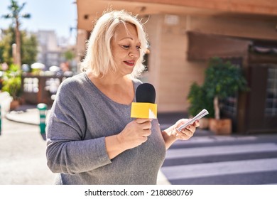 Middle Age Blonde Woman Reporter Working Using Microphone At Street