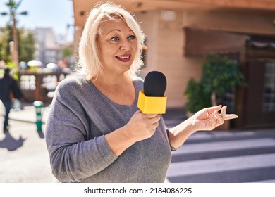 Middle Age Blonde Woman Reporter Working Using Microphone At Street