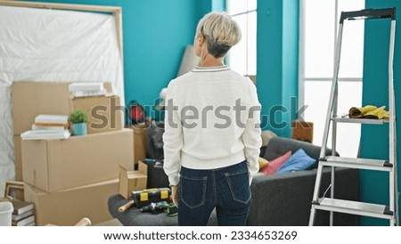 Middle age blonde woman standing backwards at new home
