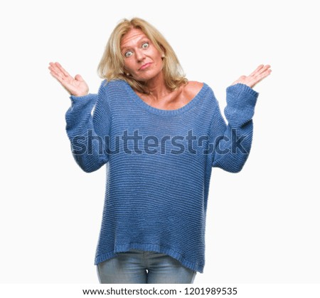 Middle age blonde woman wearing winter sweater over isolated background clueless and confused expression with arms and hands raised. Doubt concept.
