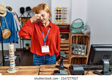 Middle age blonde woman working working as manager at retail boutique tired rubbing nose and eyes feeling fatigue and headache. stress and frustration concept. 