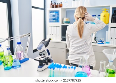 Middle Age Blonde Woman Working At Scientist Laboratory Backwards Thinking About Doubt With Hand On Head 