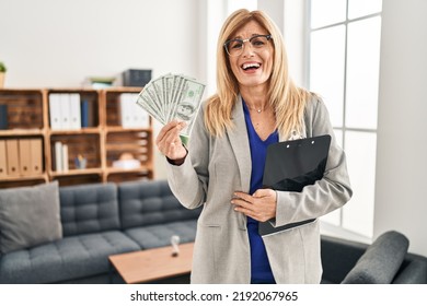 Middle Age Blonde Woman Working At Therapy Consultation Office Holding Money Smiling And Laughing Hard Out Loud Because Funny Crazy Joke. 