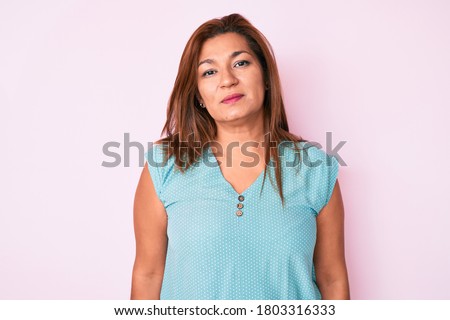 Middle age brunette hispanic woman wearing casual clothes relaxed with serious expression on face. simple and natural looking at the camera. 