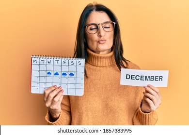 Middle Age Brunette Woman Holding December Calendar Looking At The Camera Blowing A Kiss Being Lovely And Sexy. Love Expression. 