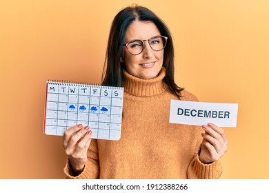 Middle Age Brunette Woman Holding December Calendar Winking Looking At The Camera With Sexy Expression, Cheerful And Happy Face. 