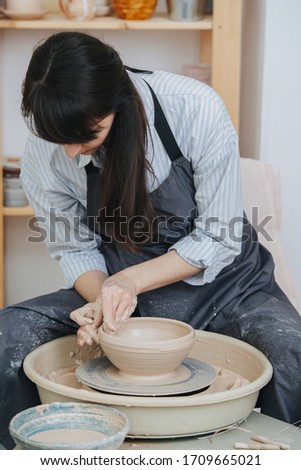 Similar – Young female sitting by table and making clay or ceramic mug