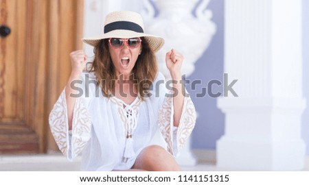 Middle age brunette woman wearing summer hat on vacations annoyed and frustrated shouting with anger, crazy and yelling with raised hand, anger concept