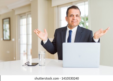 Middle age business man working with computer laptop clueless and confused expression with arms and hands raised. Doubt concept. - Powered by Shutterstock