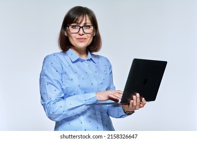 Middle Age Business Woman Using Laptop, Looking At Camera On Light Background