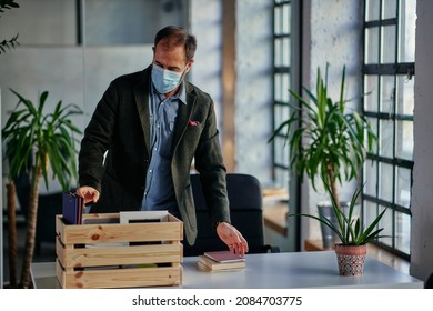 Middle Age Businessman With Protective Face Mask Unpack His Box With Belongings. He Return To Work In The Office