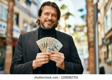 Middle Age Businessman Smiling Happy Holding Dollars At The City.