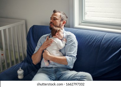 Middle Age Caucasian Father With Sleeping Newborn Baby Girl. Parent Holding Rocking Child Daughter Son In Hands. Authentic Lifestyle Parenting Fatherhood Moment. Single Dad Family Home Life.