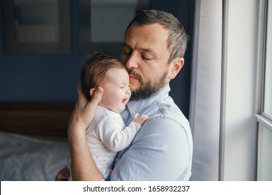 Middle Age Caucasian Father Trying To Calm Down Newborn Baby. Man Parent Holding Rocking Child On His Hands. Authentic Lifestyle Family Moment. Single Dad Home Life Concept. 