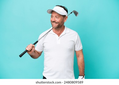 Middle age caucasian golfer player man isolated on blue background looking to the side and smiling - Powered by Shutterstock