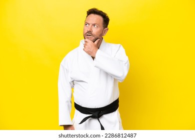 Middle age caucasian man doing karate isolated on yellow background having doubts - Powered by Shutterstock