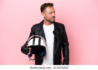 Middle Age Caucasian Man With A Motorcycle Helmet Isolated On Pink Background Looking To The Side