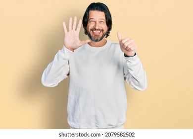 Middle age caucasian man wearing casual clothes showing and pointing up with fingers number six while smiling confident and happy.  - Shutterstock ID 2079582502