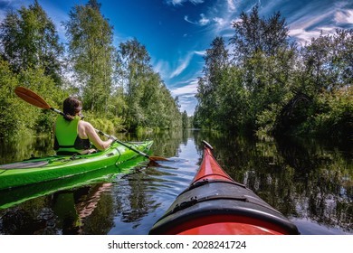 Middle age Caucasian Scandinavian women kayaking in small river Savaron in forest, sunny summer day, excellent summer activity Northern Sweden, Umea, Savar. Clear blue sky with white clouds - Powered by Shutterstock