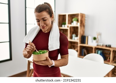 Middle age caucasian sporty woman eating salad at home.