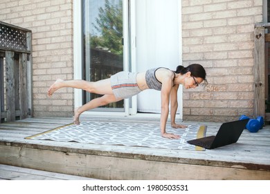 Middle Age Caucasian Woman Doing Push-ups Exercises On Home Backyard Online. Video Fitness Sport Workout On Internet. Woman Learning In Training Class With Laptop. New Normal. Sport At Home.