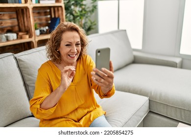 Middle Age Caucasian Woman Having Video Call Using Smartphone Sitting On The Sofa At Home.