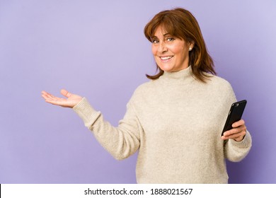 Middle Age Caucasian Woman Holding A Phone Showing A Copy Space On A Palm And Holding Another Hand On Waist.