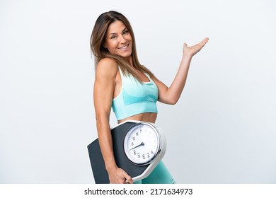 Middle age caucasian woman isolated on white background with weighing machine