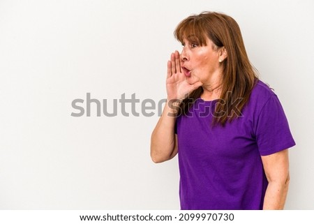 Middle age caucasian woman isolated on white background is saying a secret hot braking news and looking aside