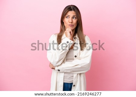 Middle age caucasian woman isolated on pink background having doubts and thinking