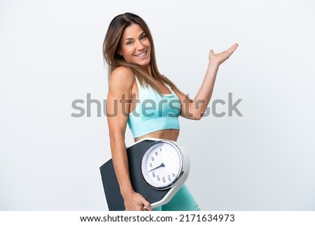 Middle age caucasian woman isolated on white background with weighing machine