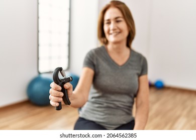 Middle age caucasian woman smiling confident training using grip hand at sport center
