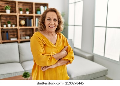 Middle age caucasian woman smiling happy standing with arms crossed gesture at home.