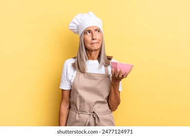 middle age chef woman feeling sad, upset or angry and looking to the side with a negative attitude, frowning in disagreement and holding an empty pot - Powered by Shutterstock