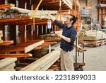Middle age Chinese man buying wood planks at home improvement retail store for DIY construction project