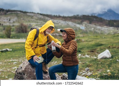 Middle age couple with backpack taking break of hiking in a beautiful nature and taking tea or water from a thermos flask - Powered by Shutterstock