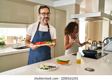 Middle Age Couple Cooking Mediterranean Food At Home Smiling Looking To The Side And Staring Away Thinking. 