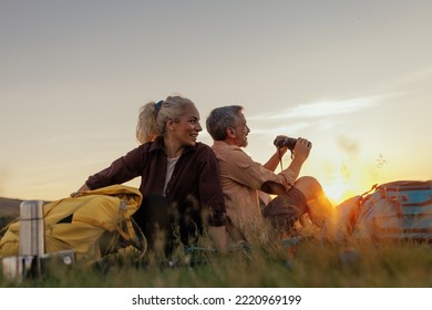 Middle age couple during their hike with backpacks. Sitting on meadow with their backs to each other and chilling - Powered by Shutterstock