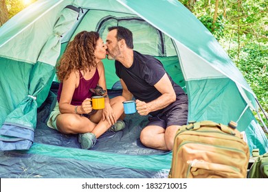 Middle Age Couple  Of Hiker Kissing Holding Cup Of Coffee Camping At The Forest.