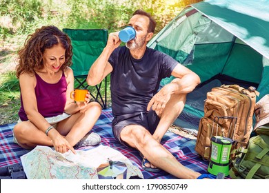 Middle Age Couple  Of Hiker Smiling Happy Drinking Coffee. Looking At The Map Camping At The Forest