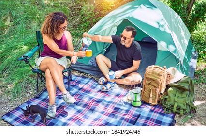 Middle Age Couple  Of Hiker Smiling Happy Drinking Coffee Camping At The Forest.