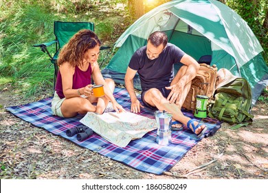 Middle Age Couple  Of Hiker Smiling Happy Drinking Coffee. Looking At The Map Camping At The Forest