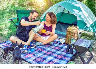 Middle Age Couple  Of Hiker Smiling Happy Drinking Coffee Camping At The Forest.