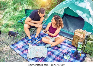 Middle Age Couple  Of Hiker Smiling Happy Camping At The Forest. Sitting On The Floor Using Smartphone.